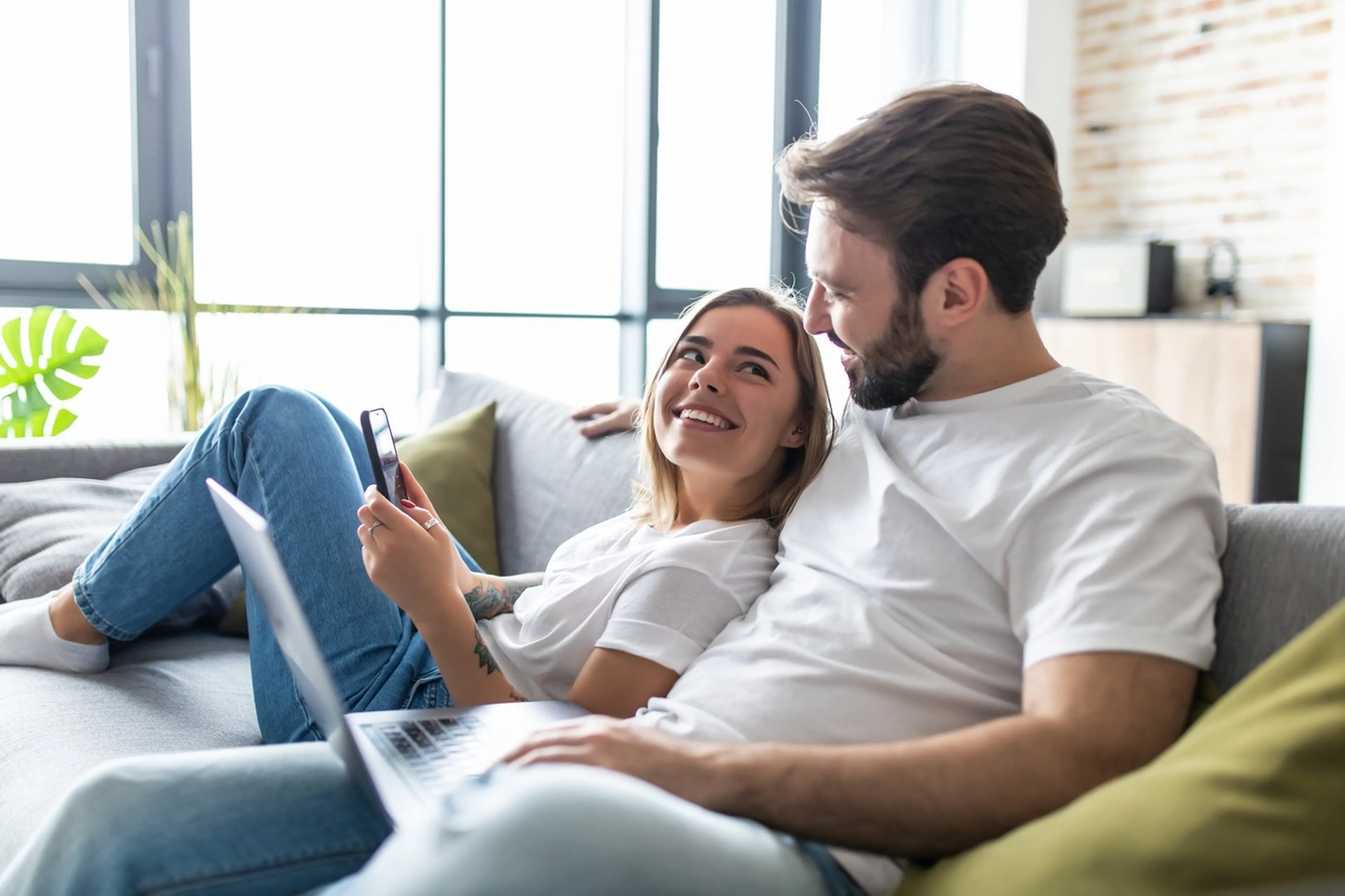 Paar sitzt auf Sofa und lächelt sich an