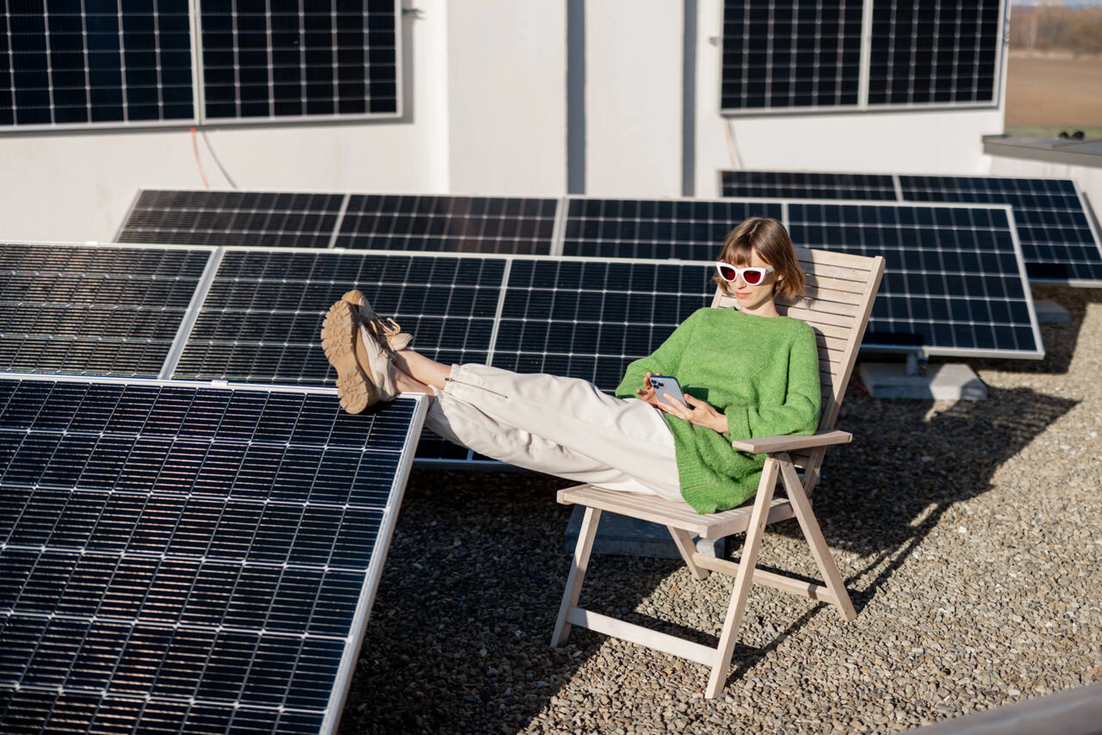 Frau sitzt mit einem Klappstuhl in einem PV-Park