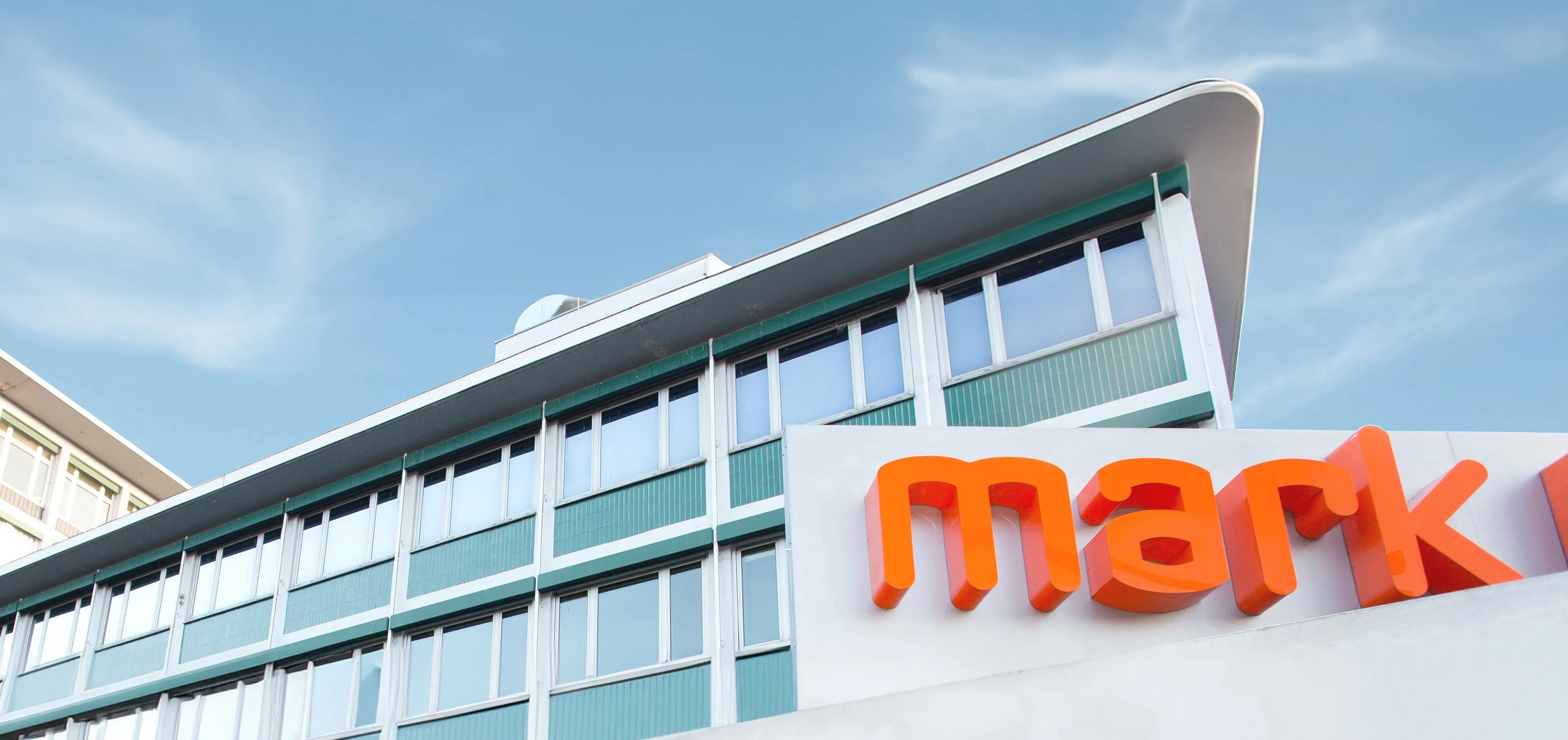 Gebäude mit Mark-E Schriftzug in Orange und blauem Himmel im Hintergrund
